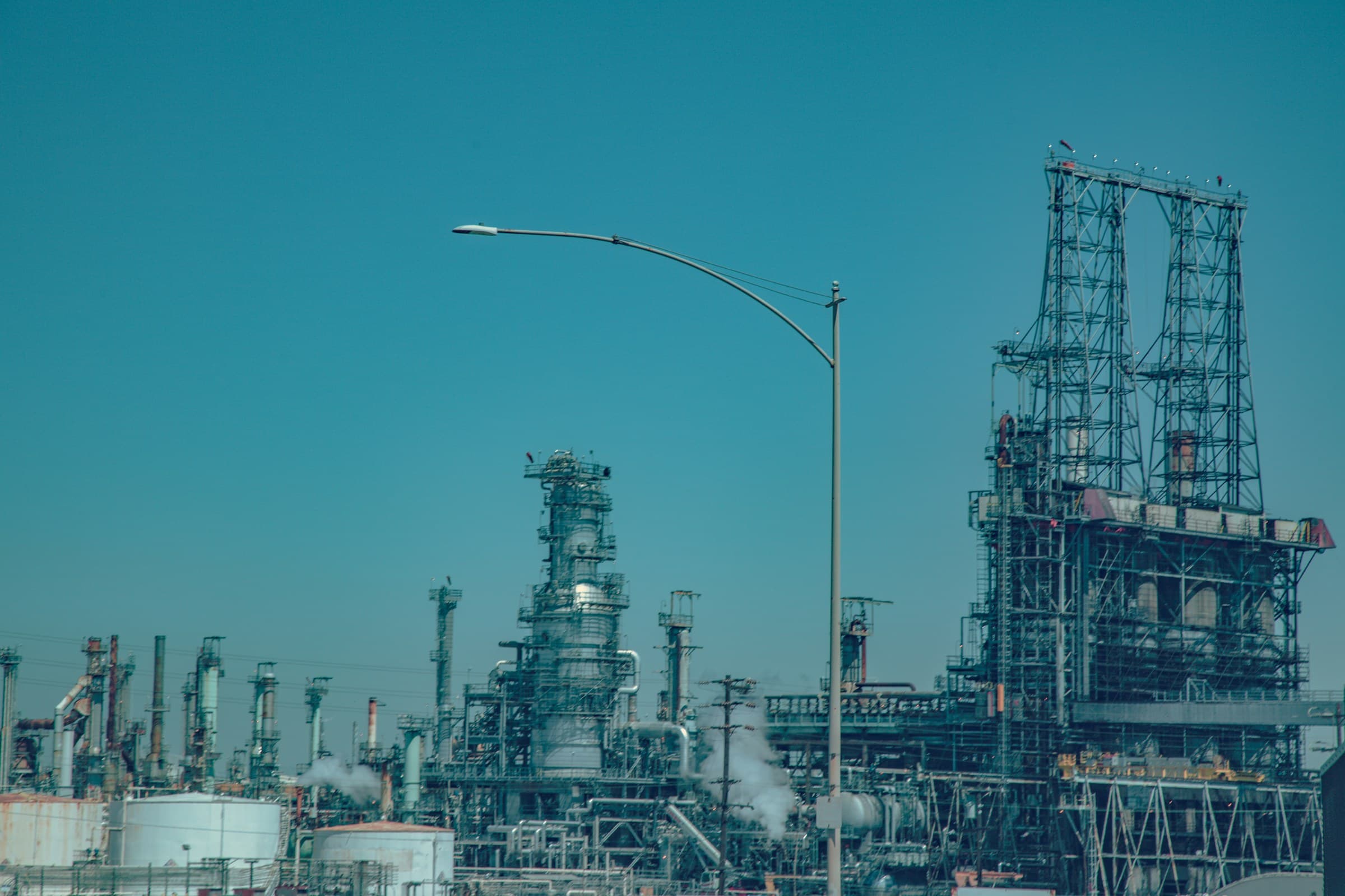 Industrial oil and gas refinery complex with processing towers and piping under a clear sky